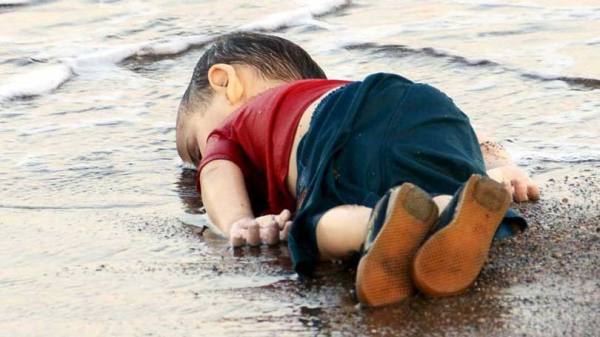 A imagem que chocou o mundo. Nome do menino: Alyan Kurdi. Nacionalidade: síria. Idade: apenas, três anos. Ele tinha escapado das atrocidades do grupo autointitulado "Estado Islâmico" na Síria.